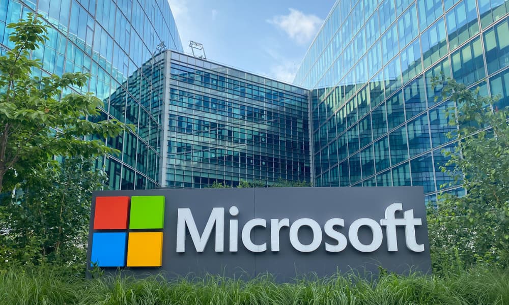 The image displays the front of a Microsoft office building with glass windows.
