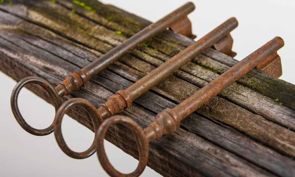 The image displays three rusty antique keys resting on aged wood.  